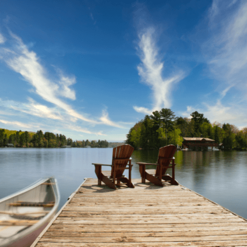 Muskoka chairs on a dock beside a canoe (1)